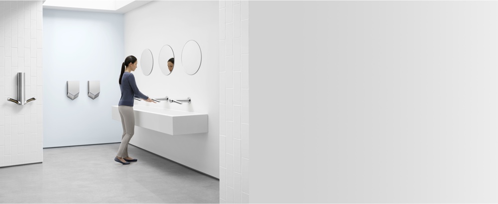 Moteris, plaunanti rankas naudojant „Dyson Airblade“ rankų plovimo ir džiovinimo prietaisą 